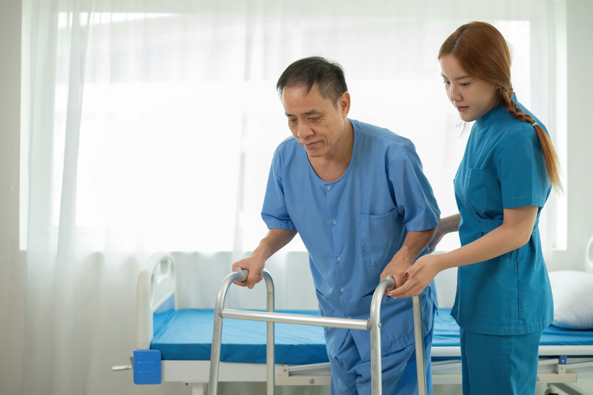 A sick caregiver or young nurse is helping a patient who is rehabilitating with physical therapy at