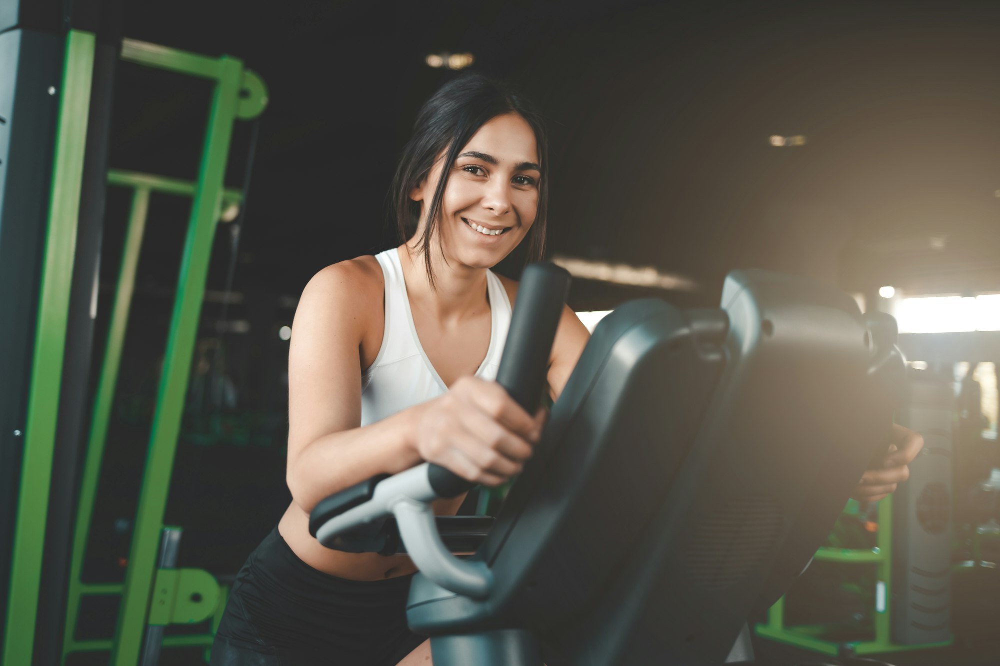 Fitness girl is engaged on a stationary bike. Pretty young woman loses weight in the gym