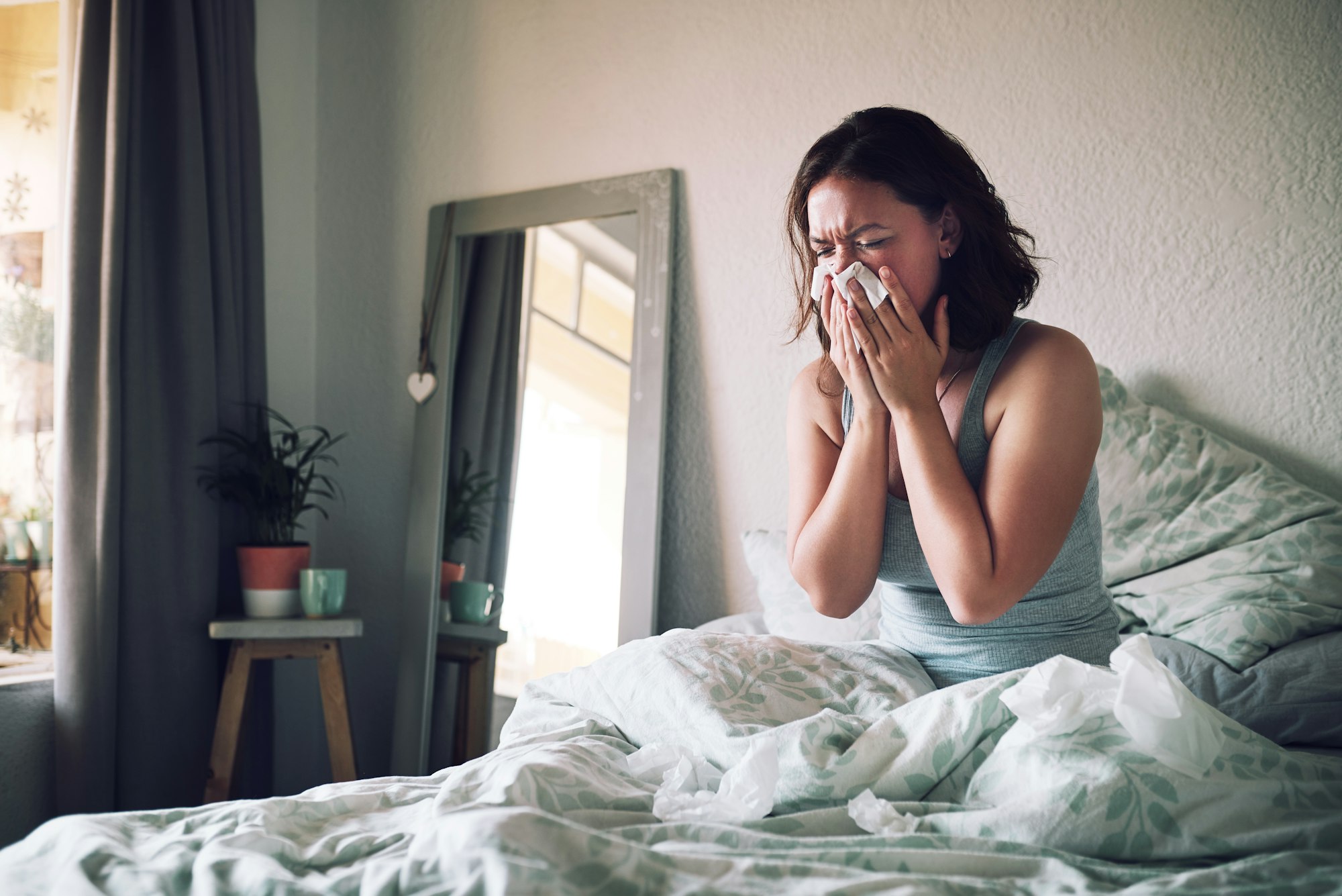 Shot of an attractive young woman suffering with the flu while sitting on her bed at home